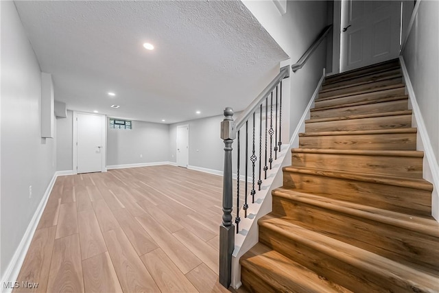 stairway with baseboards, a textured ceiling, recessed lighting, and wood finished floors
