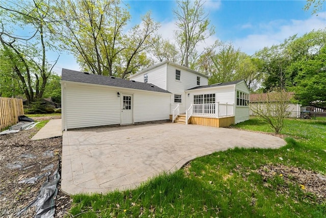 rear view of property with a yard, fence, a patio area, and a sunroom