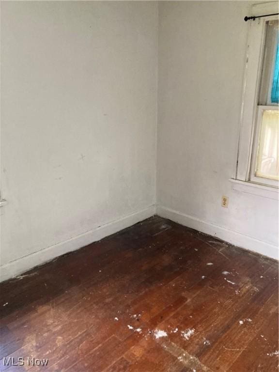 spare room featuring baseboards and dark wood-style flooring