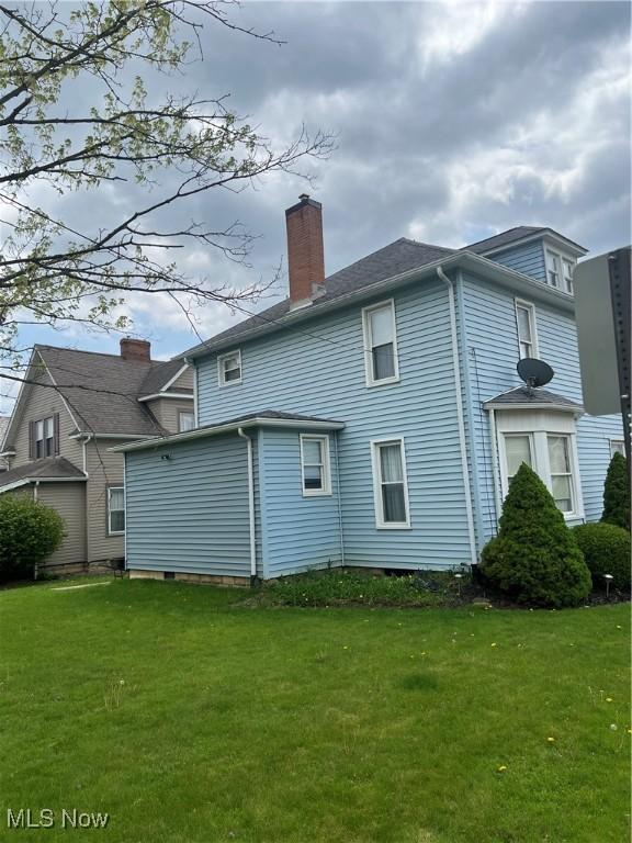 rear view of house with a lawn and a chimney