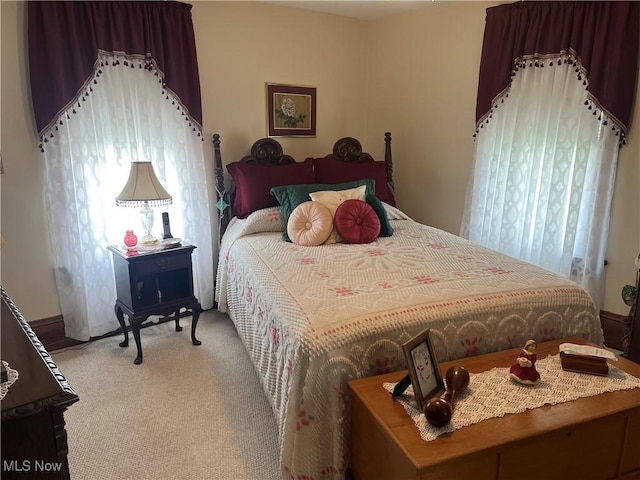 bedroom with baseboards and light colored carpet
