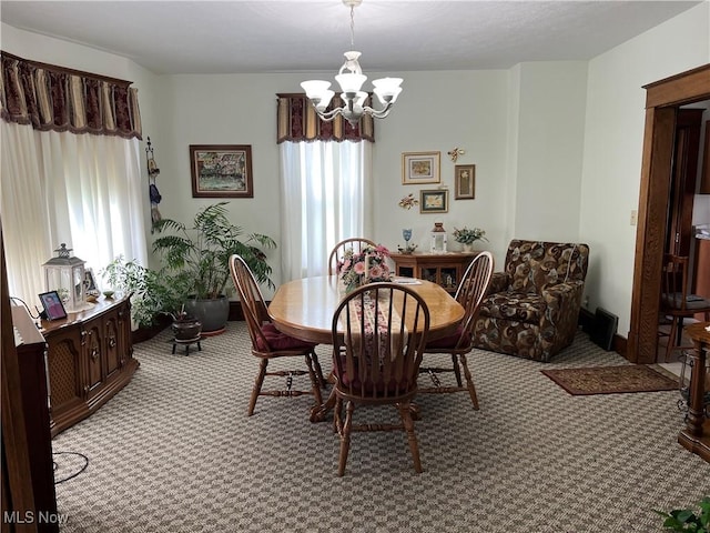 carpeted dining room with an inviting chandelier and baseboards