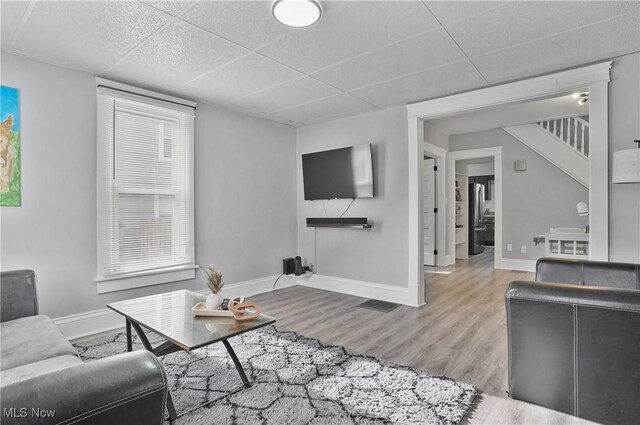 288 College St, Wadsworth, OH 44281 - living room featuring baseboards, stairs, a paneled ceiling, and wood finished floors