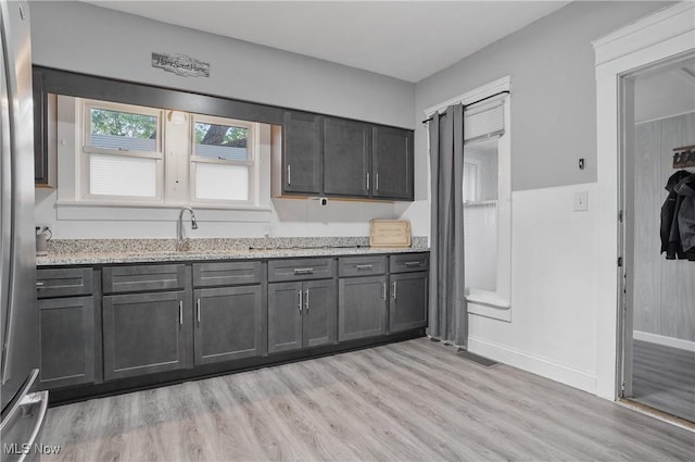 288 College St, Wadsworth, OH 44281 - kitchen with freestanding refrigerator, light stone countertops, baseboards, light wood-type flooring, and a sink