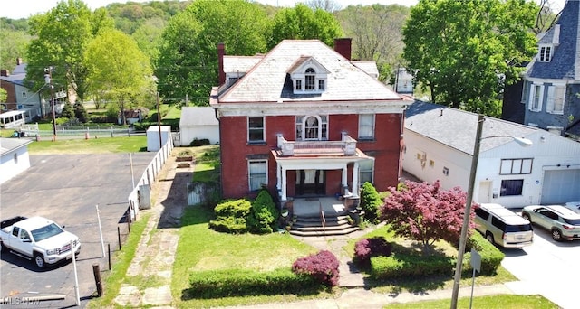 view of front of house featuring fence, a balcony, covered porch, a chimney, and brick siding