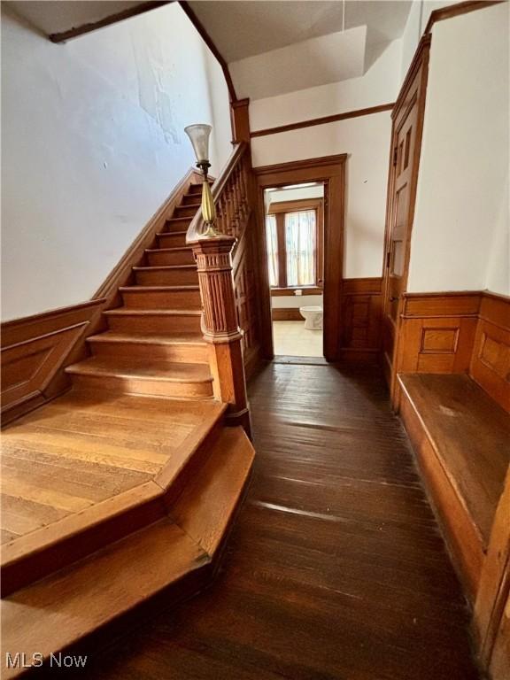 stairs featuring wainscoting and hardwood / wood-style floors