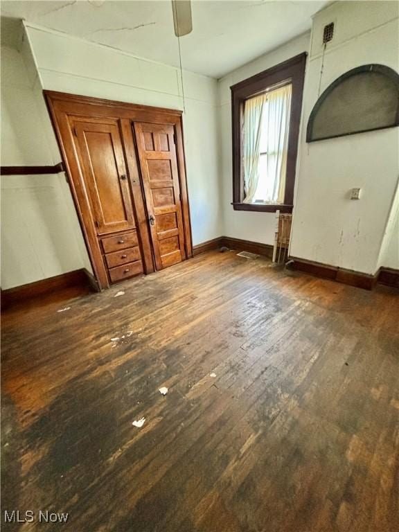 unfurnished bedroom featuring baseboards, ceiling fan, and dark wood-type flooring