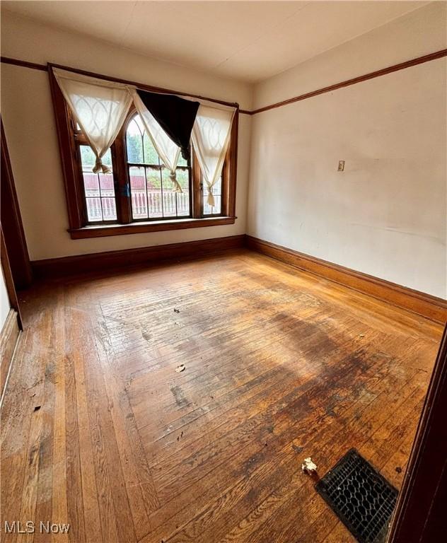 unfurnished room with baseboards and hardwood / wood-style floors