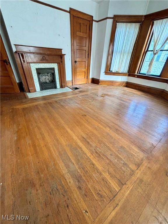 unfurnished living room featuring wood-type flooring, baseboards, and a fireplace