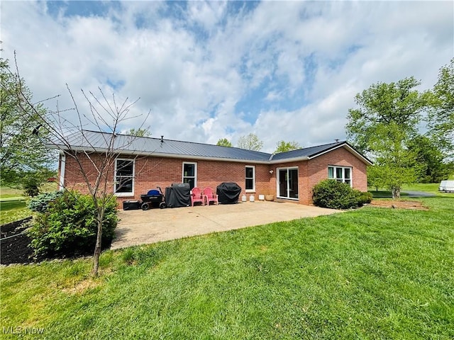rear view of property with brick siding, a patio, and a yard