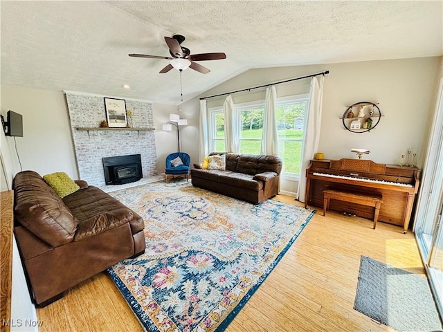 living room featuring a textured ceiling, ceiling fan, wood finished floors, and vaulted ceiling