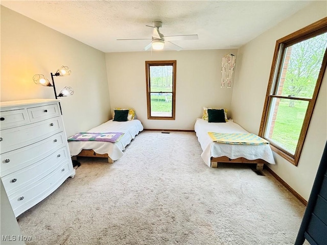 bedroom with a ceiling fan, light colored carpet, and multiple windows