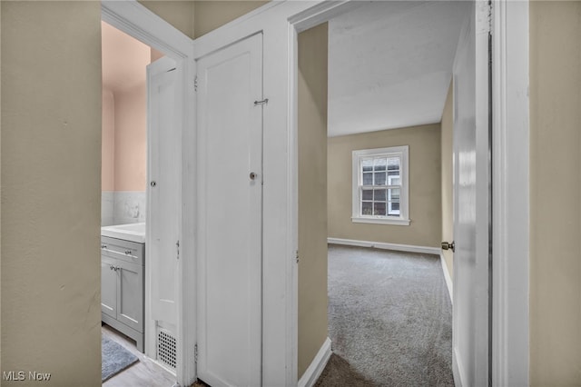 corridor featuring baseboards and carpet flooring