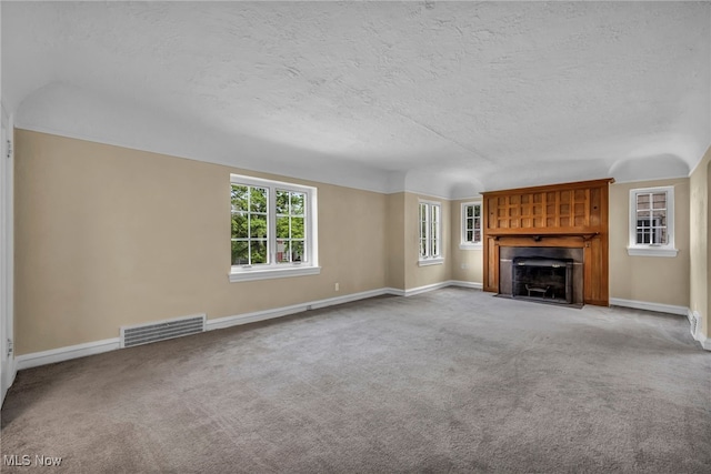 unfurnished living room with baseboards, plenty of natural light, a textured ceiling, and visible vents