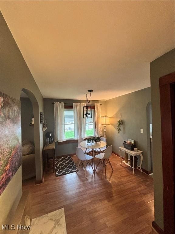 dining room with arched walkways and wood finished floors