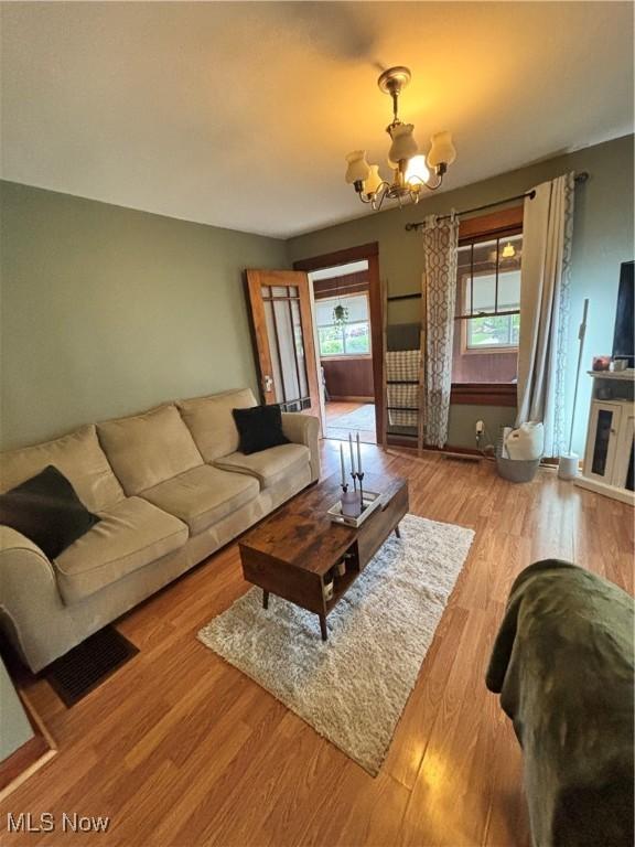 living area featuring an inviting chandelier, wood finished floors, and visible vents