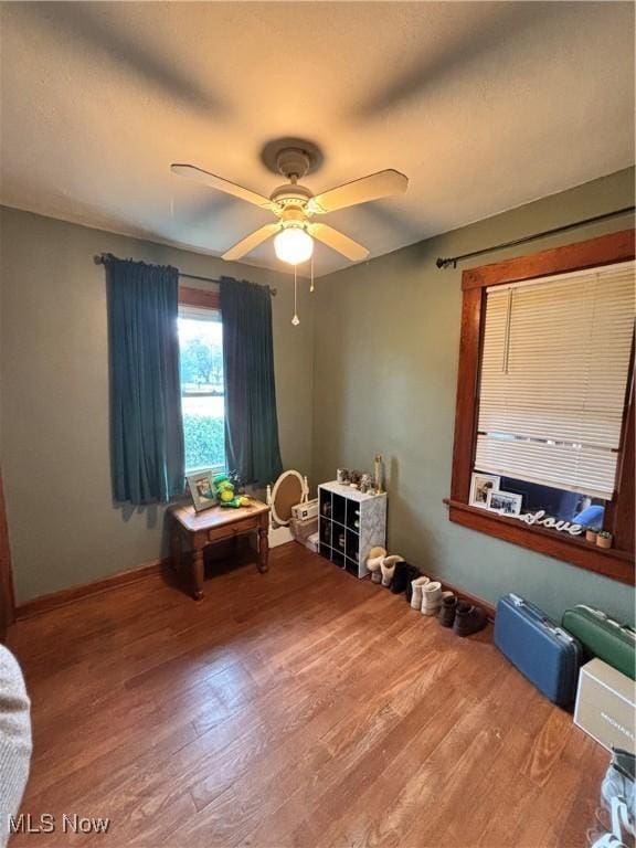 interior space with baseboards, a ceiling fan, and wood finished floors