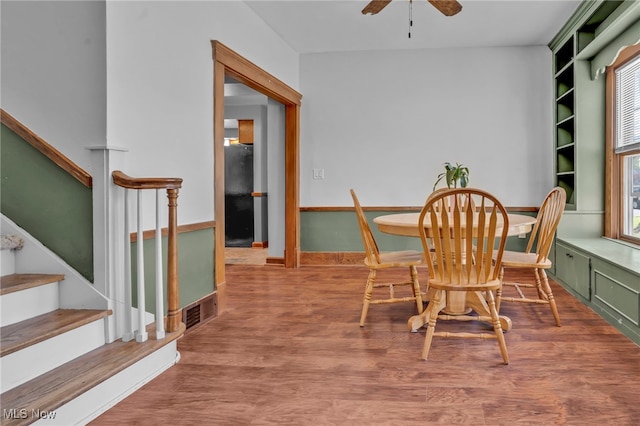 dining area with plenty of natural light, a ceiling fan, stairs, and wood finished floors