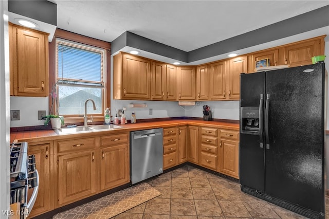 kitchen with stainless steel dishwasher, recessed lighting, a sink, light tile patterned floors, and black fridge