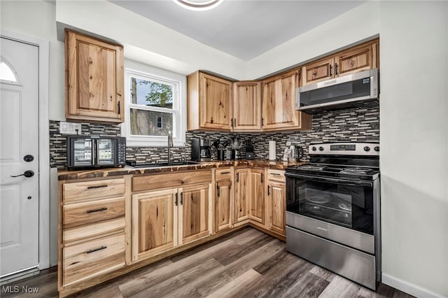 838 N Lincoln Ave, Alliance, OH 44601 - kitchen with decorative backsplash, dark wood-style flooring, dark countertops, a sink, and appliances with stainless steel finishes