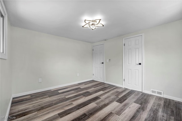838 N Lincoln Ave, Alliance, OH 44601 - unfurnished bedroom with baseboards, visible vents, and dark wood-type flooring