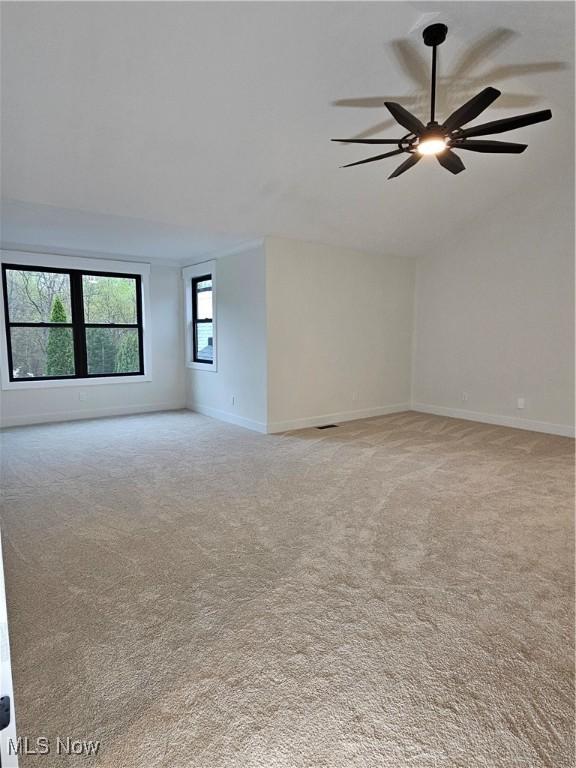spare room featuring baseboards, a ceiling fan, and light carpet