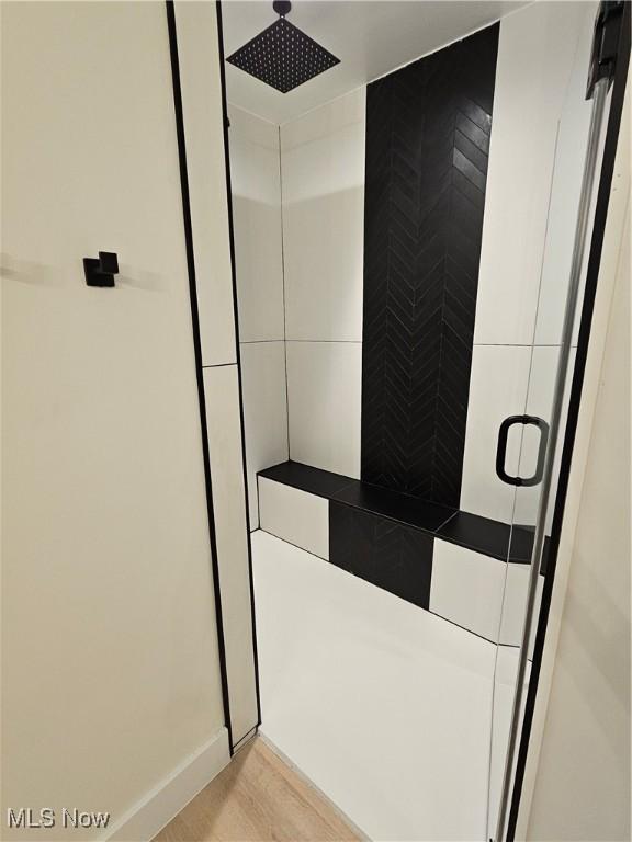 full bathroom featuring baseboards, a stall shower, and wood finished floors