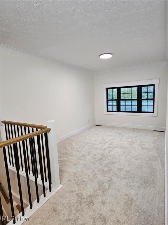 unfurnished room with carpet floors, ornamental molding, and baseboards