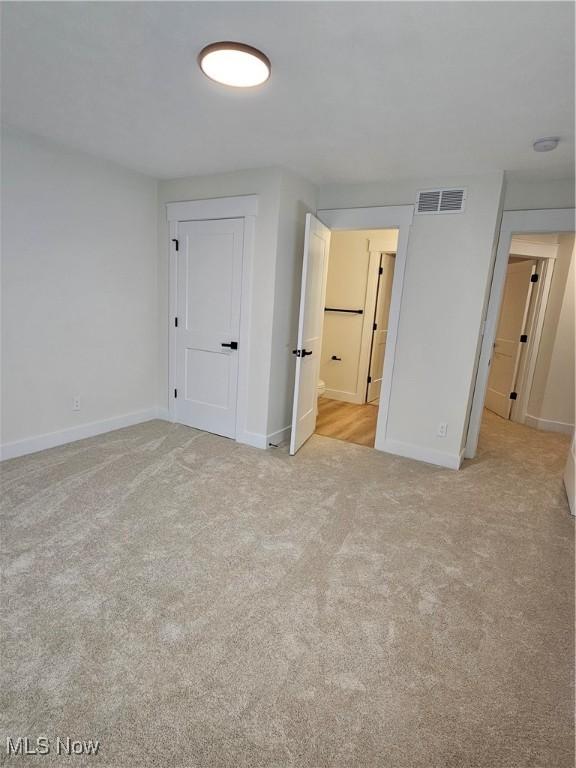 unfurnished bedroom featuring carpet flooring, baseboards, and visible vents