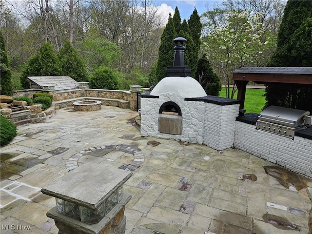 view of patio / terrace with exterior kitchen, an outdoor fire pit, exterior fireplace, and a grill