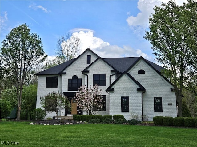 french country style house with brick siding and a front yard