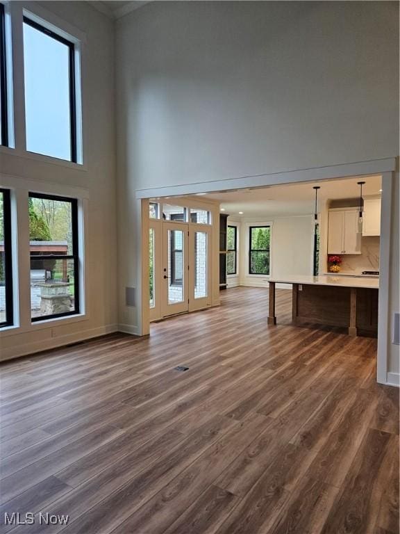 unfurnished living room featuring baseboards, dark wood-style flooring, and a high ceiling