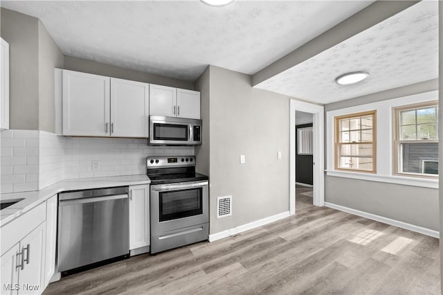1335 W Blvd, Cleveland, OH 44102 - kitchen featuring light wood finished floors, light countertops, stainless steel appliances, baseboards, and visible vents