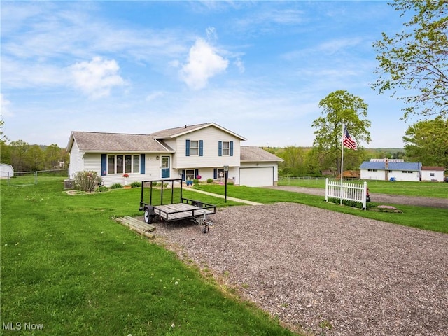 rear view of property featuring fence, a yard, gravel driveway, and a garage