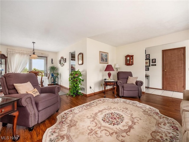 living area with baseboards, visible vents, and wood finished floors