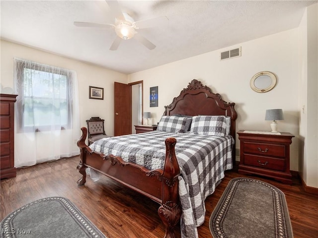 bedroom featuring baseboards, ceiling fan, visible vents, and wood finished floors