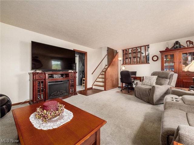 carpeted living area featuring baseboards, a fireplace, and stairs