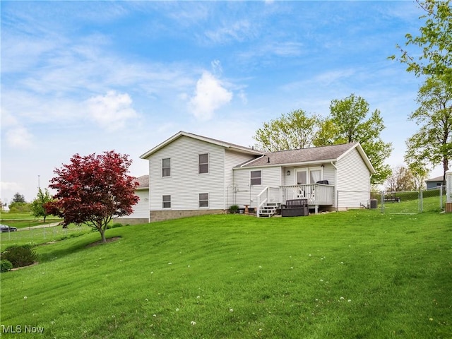 back of property with a lawn, fence, and a wooden deck