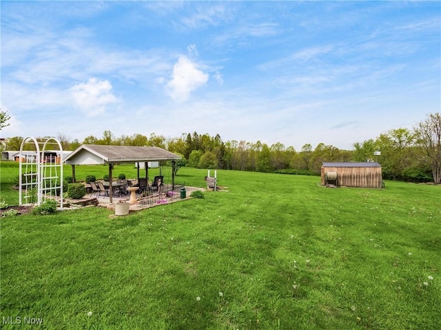 view of yard featuring a gazebo, an outdoor structure, a patio area, and a storage shed