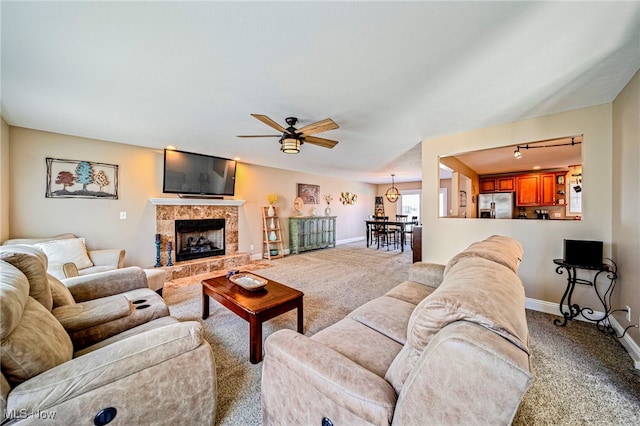 living area with carpet floors, a ceiling fan, baseboards, and a tiled fireplace