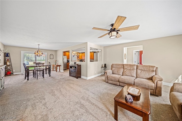living area featuring baseboards, ceiling fan with notable chandelier, and light colored carpet