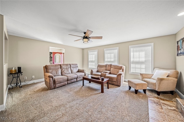 living room featuring baseboards, a ceiling fan, and light carpet
