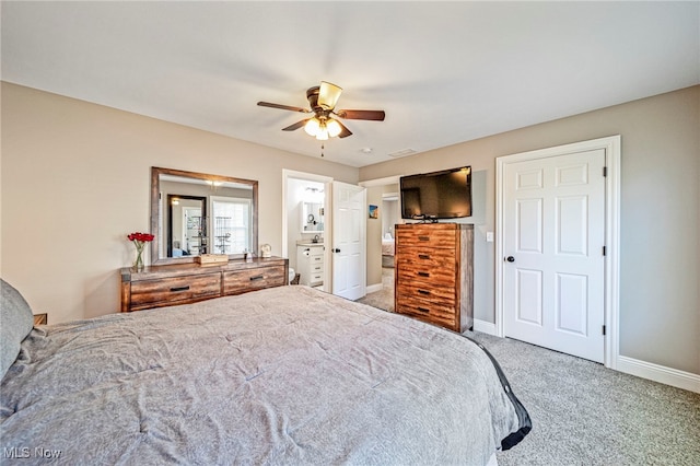carpeted bedroom with a ceiling fan, baseboards, and ensuite bath