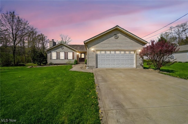 ranch-style house featuring a lawn, an attached garage, driveway, and a chimney