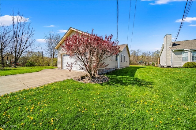 view of side of home with a yard, an attached garage, and driveway