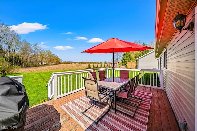 wooden terrace featuring a lawn and outdoor dining space