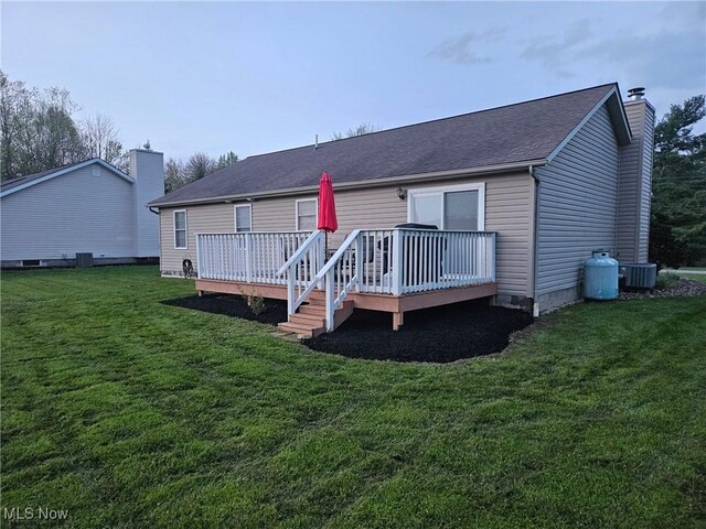 back of house with a yard, a deck, cooling unit, and a chimney