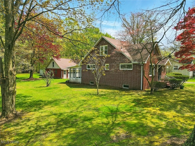 rear view of property featuring a lawn and brick siding