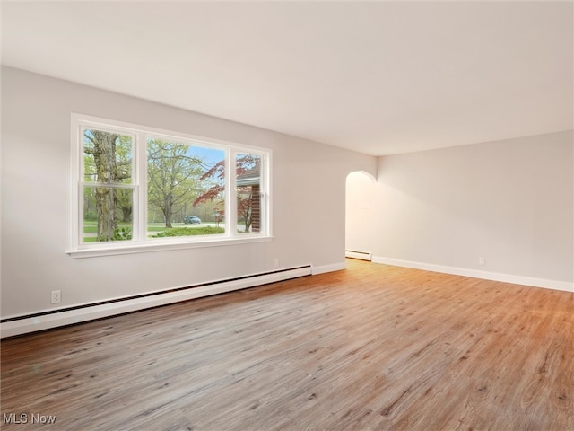 empty room with baseboards, arched walkways, wood finished floors, and baseboard heating