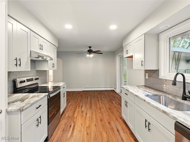 kitchen with a sink, baseboard heating, under cabinet range hood, a ceiling fan, and appliances with stainless steel finishes